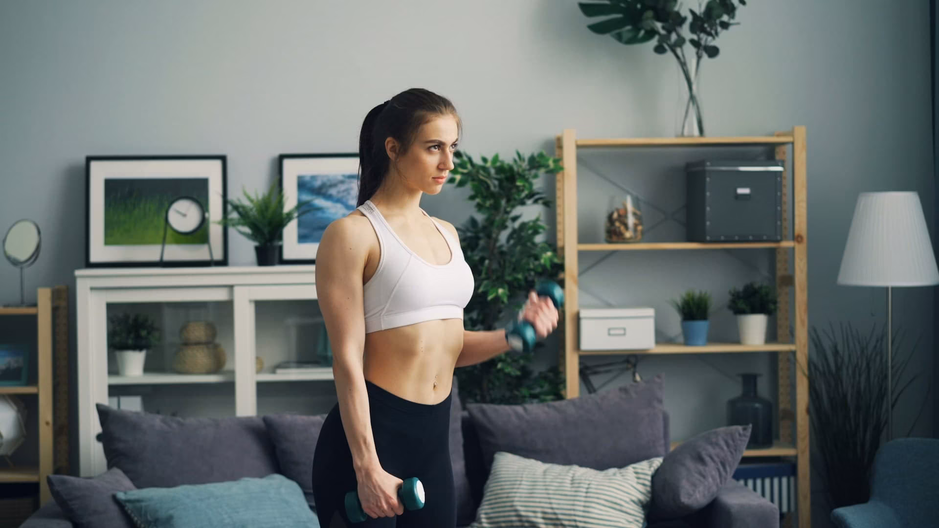 a woman in a sports bra top is holding dumbbells